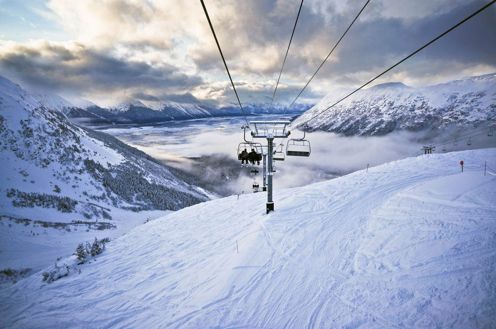 Skiers riding chairlift down mountain in Alyeska, Alaska
